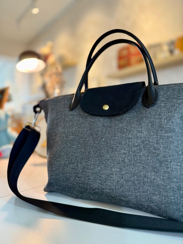 A grey fabric travel bag with navy handles