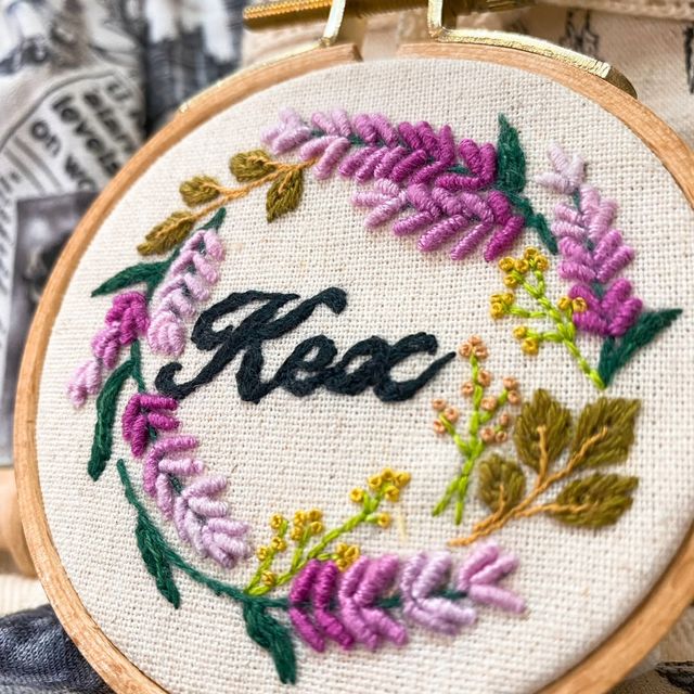 Hand embroidery: a hoop with a wreath of purple and pink flowers around the name "Kex"