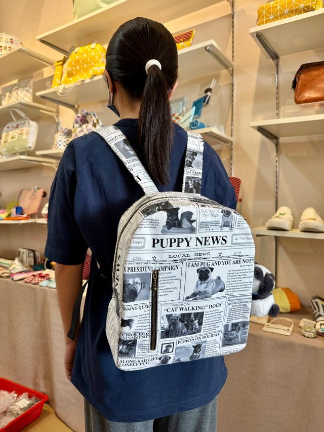 A student wearing a backpack sewn from black-and-white newspaper-print fabric