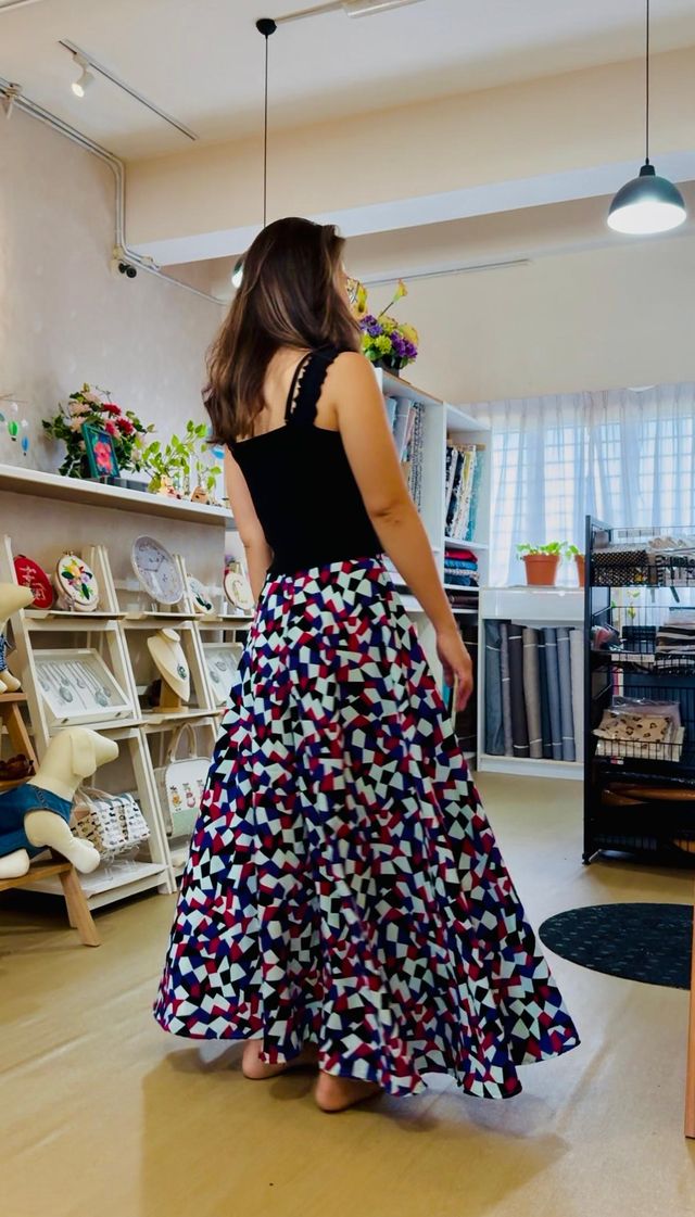 A student in the studio wearing a printed maxi skirt she sewed