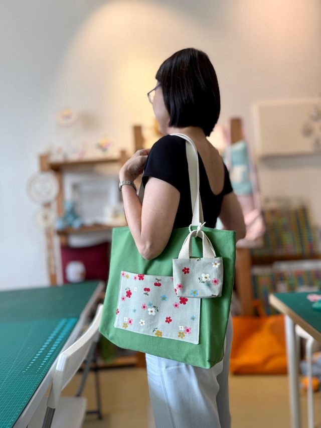 A student carrying a green tote with a matching floral mini pouch